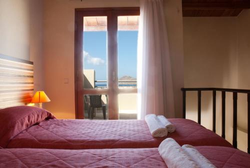a bedroom with two beds and a window with a view at Casa Maria Hotel Apts in Platanias
