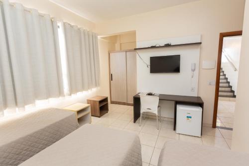 a bedroom with a bed and a desk with a television at HOTEL EXECUTIVO in Parauapebas