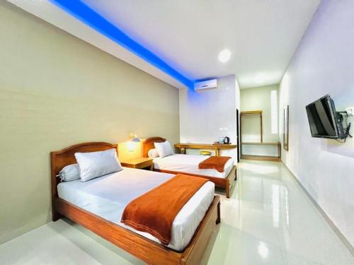 a hotel room with two beds and a tv at OASIS HOTEL in Ampana