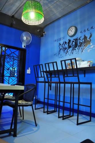 a room with chairs and a clock on a blue wall at At Home Hostel, Pak Chong in Pak Chong