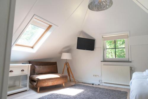 a attic room with a chair and a tv at Spacious luxury holiday home/villa - Ruime luxe vakantiewoning/-Villa in Ede