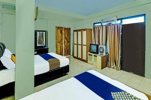 a hotel room with two beds and a television at SPOT ON 91540 Ukuh Guesthouse in Prambanan