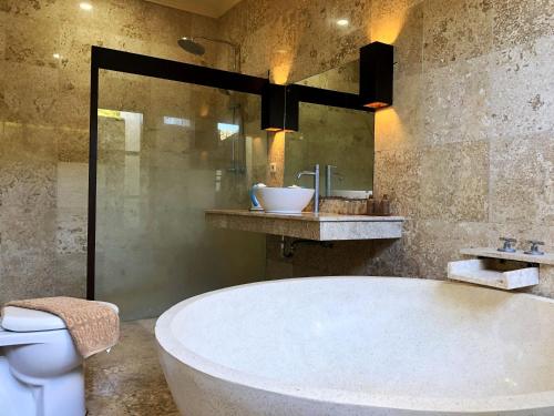 a large bath tub in a bathroom with a toilet at Lombok Sunset Bay Resort in Sekotong
