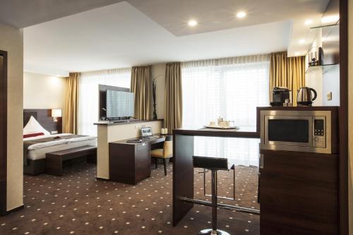 a hotel room with a bed and a desk and a television at Aparthotel DeLuxe in Oberkochen