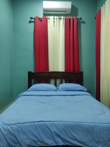 a bedroom with a bed with red and white curtains at Cassa Vistana Homestay Alor - Langgar near HSB in Alor Setar