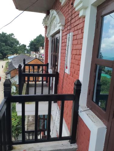 a balcony of a red brick house with a black fence at Hotel small town guest house in Bandīpur