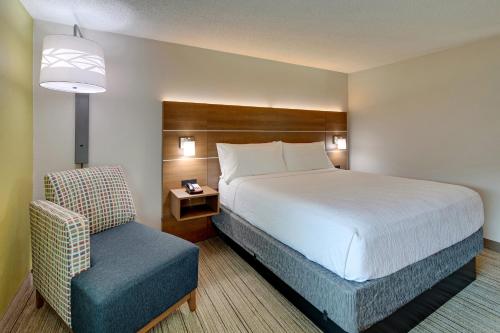Habitación de hotel con cama y silla en Holiday Inn Express Nashville W-I40, an IHG Hotel, en Nashville