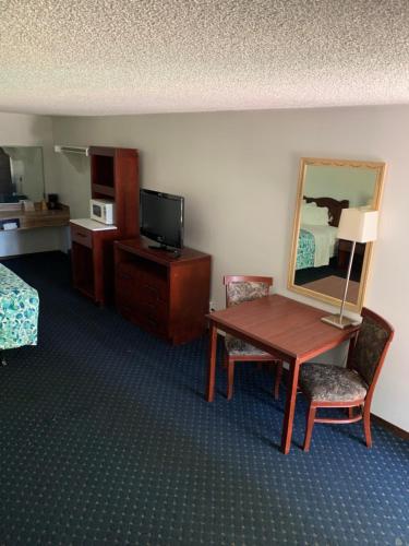 ein Hotelzimmer mit einem Tisch, einem Bett und einem Spiegel in der Unterkunft Smokey Point Motor Inn in Arlington