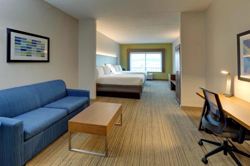 Holiday Inn Express Nashville-Opryland, an IHG Hotel في ناشفيل: غرفة في الفندق مع أريكة وسرير