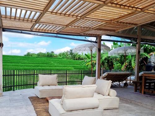 une terrasse avec des canapés blancs, des parasols et une table dans l'établissement Stay at My Place Bali, à Canggu