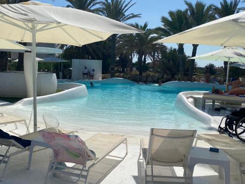a swimming pool with chairs and umbrellas at VENEZIOLA PARADISE, spa & gym in La Manga del Mar Menor