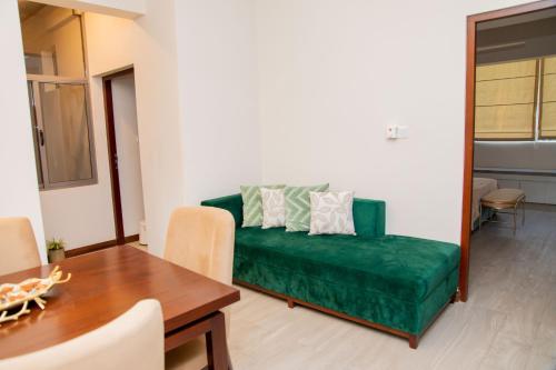 a living room with a green couch and a table at ARON'S Lavinia EMERALD in Mount Lavinia