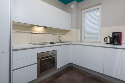 a white kitchen with white cabinets and a window at Apartments Villa Azzurra Bol in Bol
