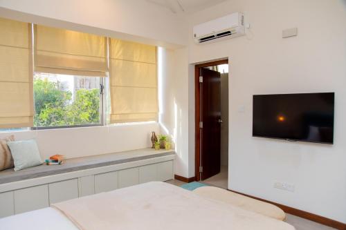 um quarto branco com uma televisão e uma janela em ARON'S Lavinia SAPPHIRE em Mount Lavinia