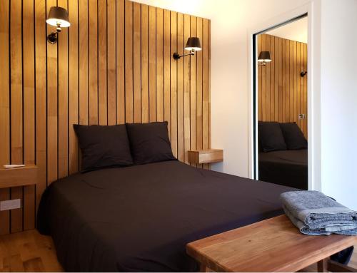 a bedroom with a black bed and a mirror at Le mazet des amants, cabane en bois avec jacuzzi privatif in Avignon