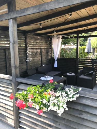 a patio with a table and flowers on a deck at Rybacka 48 - Twoje miejsce wypoczynku, domki, studia, apartamenty, rowery, hulajnogi in Jantar