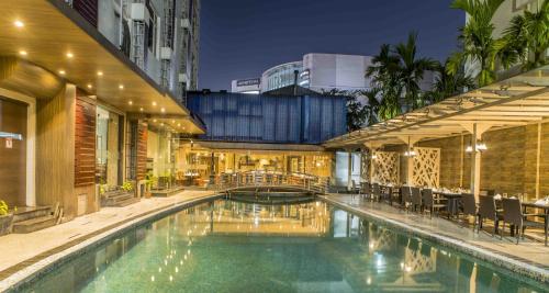 una piscina con mesas y sillas junto a un edificio en The Citi Residenci Hotel - Durgapur, en Durgāpur