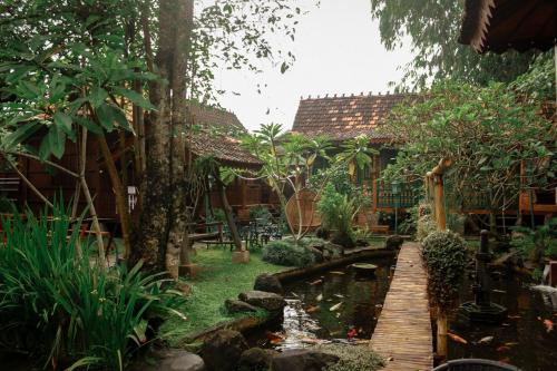 a garden with a pond in front of a house at Cokro Hinggil - Traditional View in Sleman