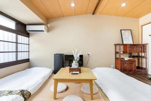 two beds in a room with a desk and a table at Minami Toji---JP Style Guesthouse in Kyoto in Kyoto