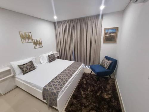 Un dormitorio con una cama y una silla azul. en Luxurious 2 Bedroom Space Available, en Accra