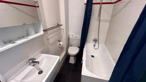 a bathroom with a toilet and a tub and a sink at Hôtel Saint James in Biarritz