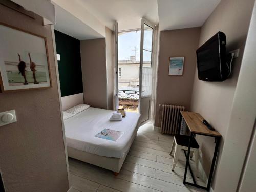 Habitación pequeña con cama y ventana en Hôtel Saint James, en Biarritz