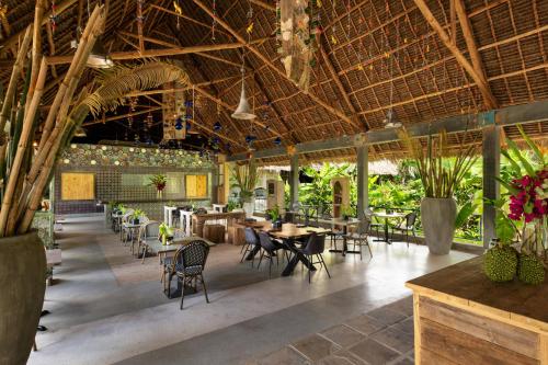 a restaurant with wooden ceilings and tables and chairs at Fun Beach Hotel in Jambiani