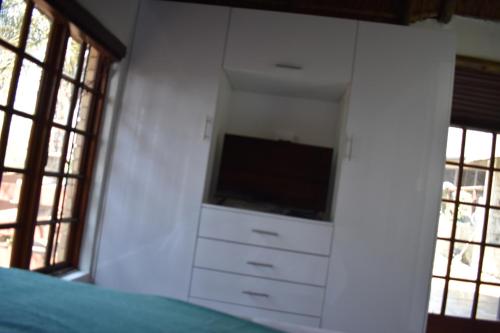 a bedroom with a dresser with a television and windows at 49 on Bristow in Roodepoort
