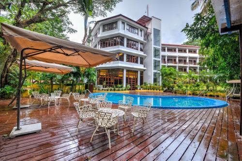 a deck with tables and chairs next to a swimming pool at Silver Sand Sentinel in Port Blair