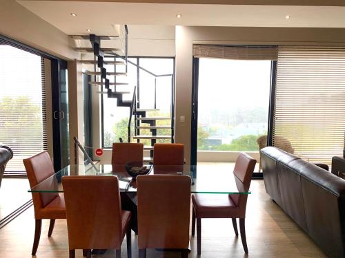 a dining room with a glass table and chairs at House Vos in Hermanus