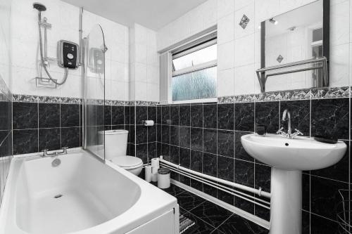 a black and white bathroom with a tub and a sink at Modern 4 bedroom home ideal for Contractors, Groups and families ,FREE parking for multiple vehicle's in Birmingham