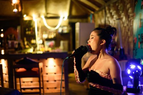 una mujer cantando en un micrófono en un bar en Silver Sand Beach Resort Havelock, en Isla Havelock