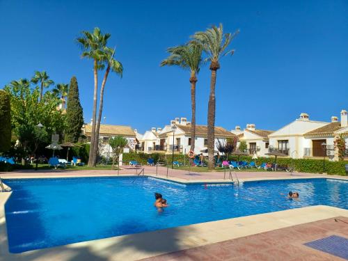 una mujer nadando en una piscina con palmeras en Apartamento Oasis, en Playas de Vera