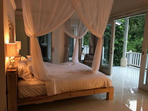 a bedroom with a canopy bed with curtains at Balian Bliss Retreat complex with private pool in Balian