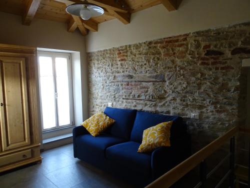 a blue couch in a room with a brick wall at La Piazza - Appartamenti Vacanza in Murazzano