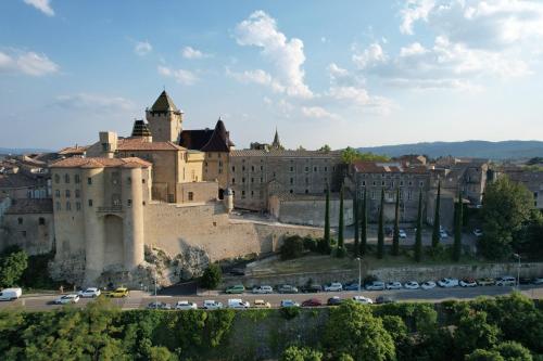 un château sur une colline avec des voitures garées dans un parking dans l'établissement Gîte 5 