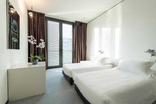 two beds in a room with white walls and windows at DUPARC Contemporary Suites in Turin