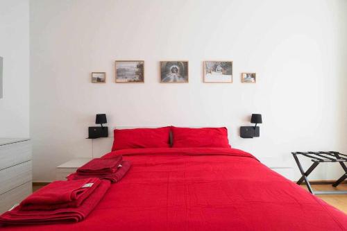 a red bed with red pillows in a white bedroom at UCA14 Luxury large apartment with private terrace in Citylife in Milan