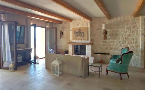 a living room with a fireplace and green chairs at RoccaSeta in Scicli