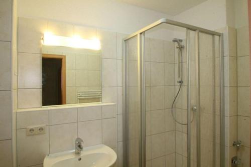 La salle de bains est pourvue d'une douche, d'un lavabo et d'un miroir. dans l'établissement Haus Odin App 24, à Graal-Müritz