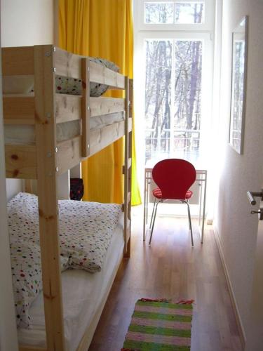 a bedroom with two bunk beds and a red chair at Haus Bucheneck App 07 in Graal-Müritz