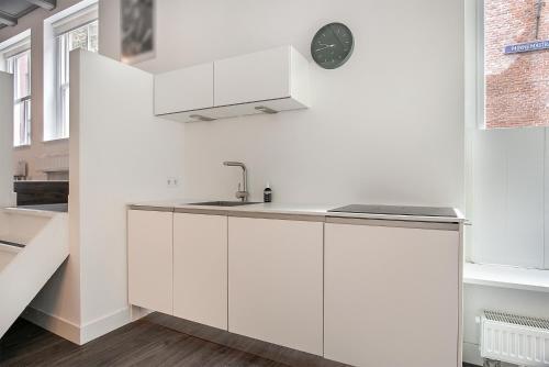 een keuken met witte kasten en een klok aan de muur bij Apartment Eewal 68 in Leeuwarden