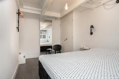 een witte slaapkamer met een bed en een stoel bij Apartment Eewal 68 in Leeuwarden