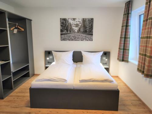 a bedroom with a bed with white sheets at Hotel Am Gleis 1 in Sonthofen