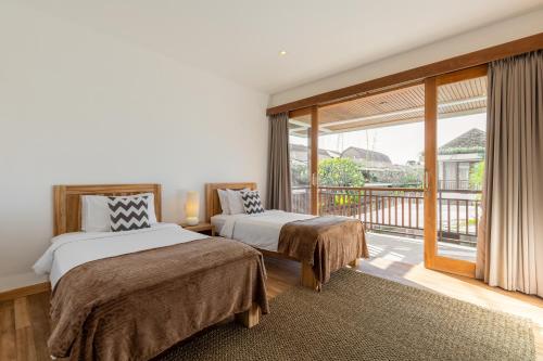 1 dormitorio con 2 camas y balcón en Villa Lumut 3 Bedrooms Central Seminyak, en Seminyak