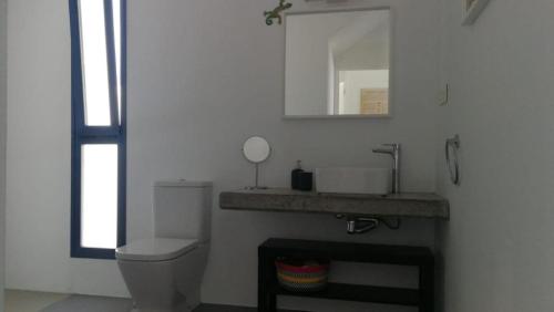een badkamer met een toilet, een wastafel en een spiegel bij Casa Galana in Punta de Mujeres