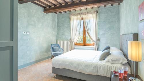 a bedroom with a bed and a chair and a window at LE RESIDENZE DEI POTTI 12, Emma Villas in Collazzone