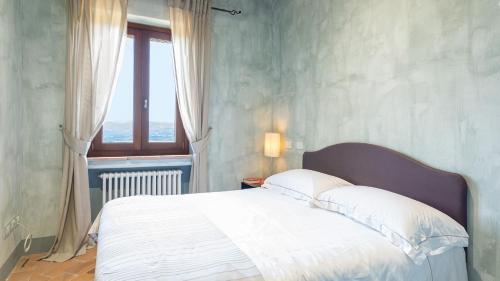 a bedroom with a white bed with a window at LE RESIDENZE DEI POTTI 12, Emma Villas in Collazzone