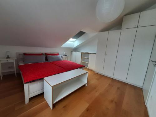 um quarto com uma cama vermelha e armários brancos em Apartment Strawberry em Bermatingen