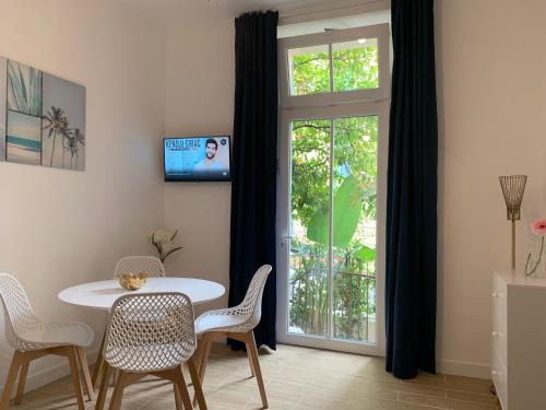 ein Esszimmer mit einem Tisch, Stühlen und einem Fenster in der Unterkunft Villa Les Fougeres 2p jardin parking in Cannes